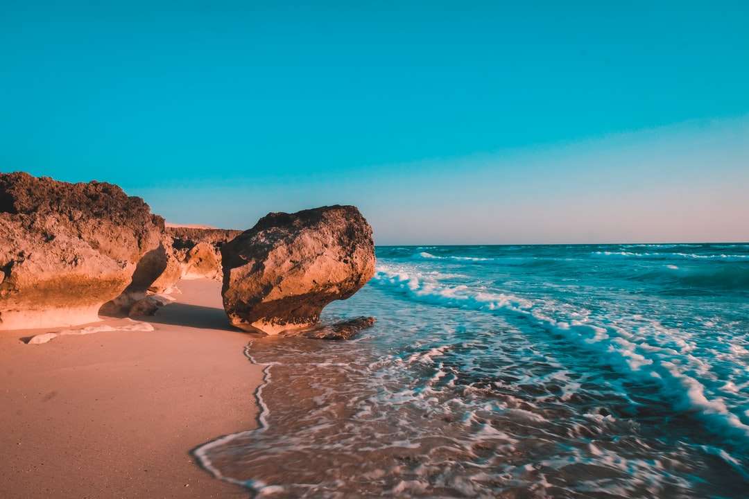 Formazione rocciosa marrone sulla riva del mare durante il giorno puzzle online