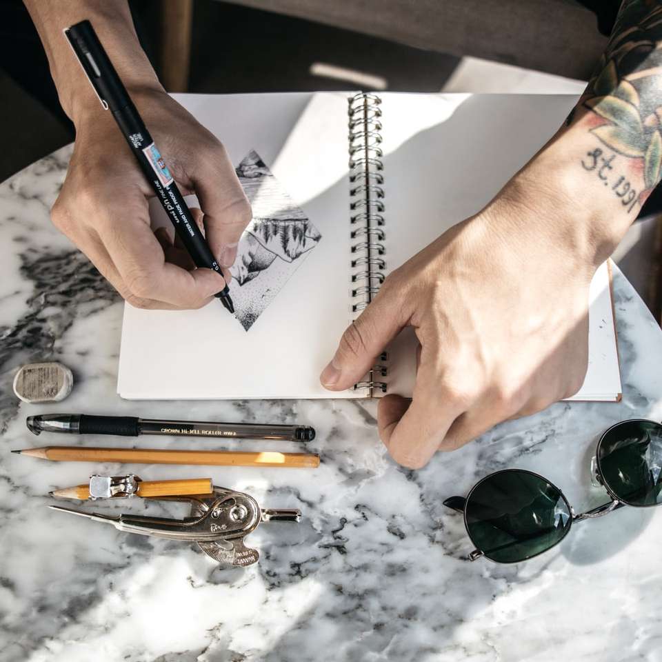 человек рисует на блокноте ручкой онлайн-пазл