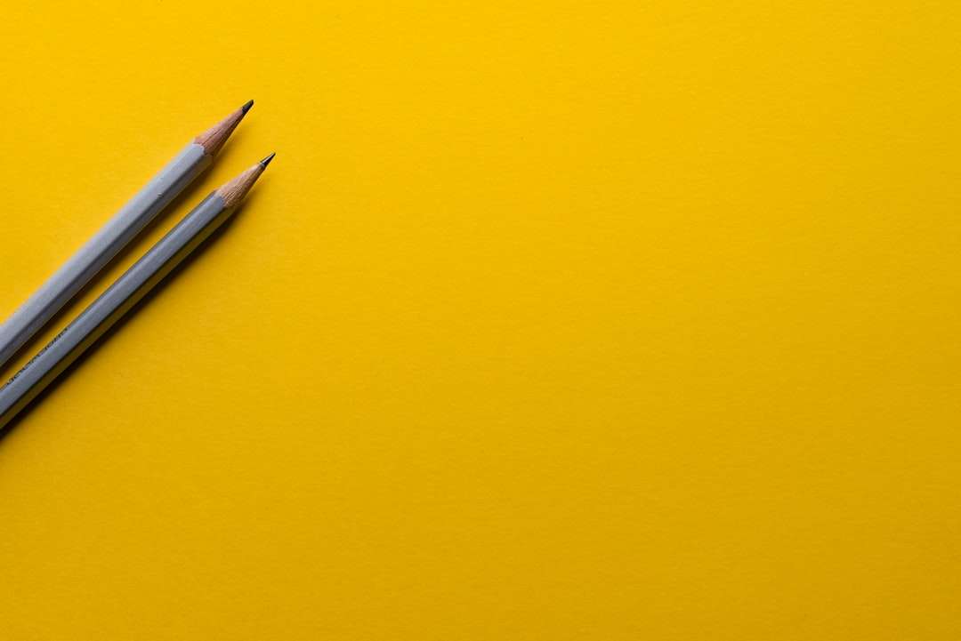 Dos lápices grises en superficie amarilla. rompecabezas en línea