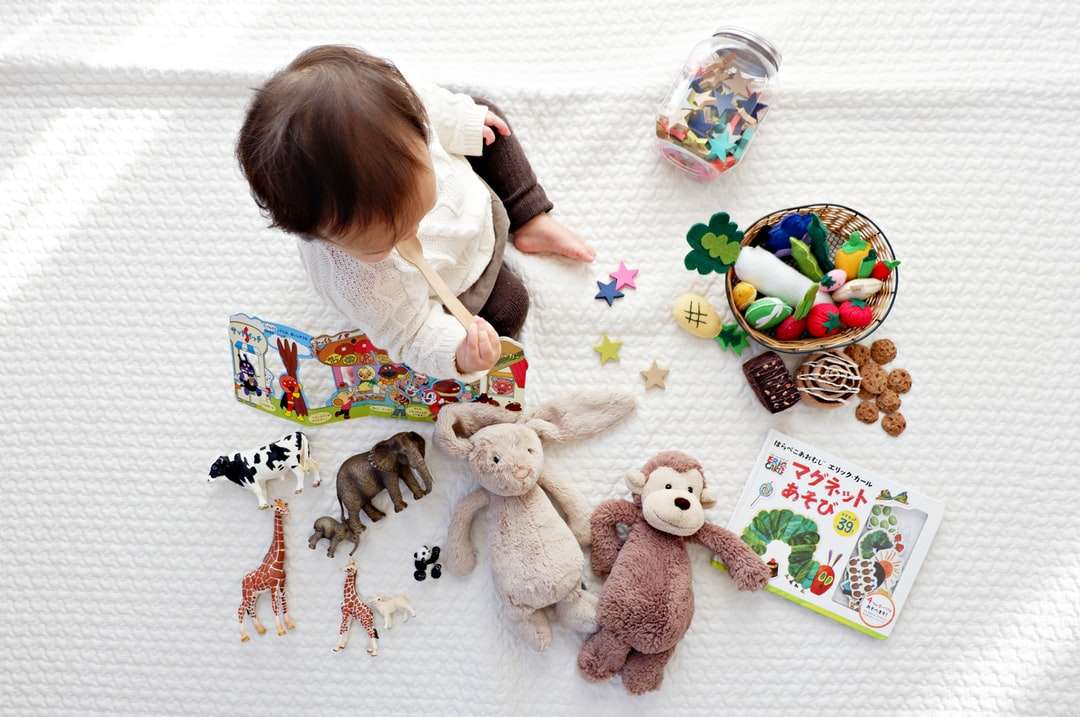 niño sentado sobre un paño blanco rodeado de juguetes rompecabezas en línea