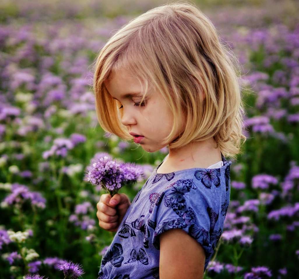 Mädchen, das purpurrote Blumen hält Online-Puzzle