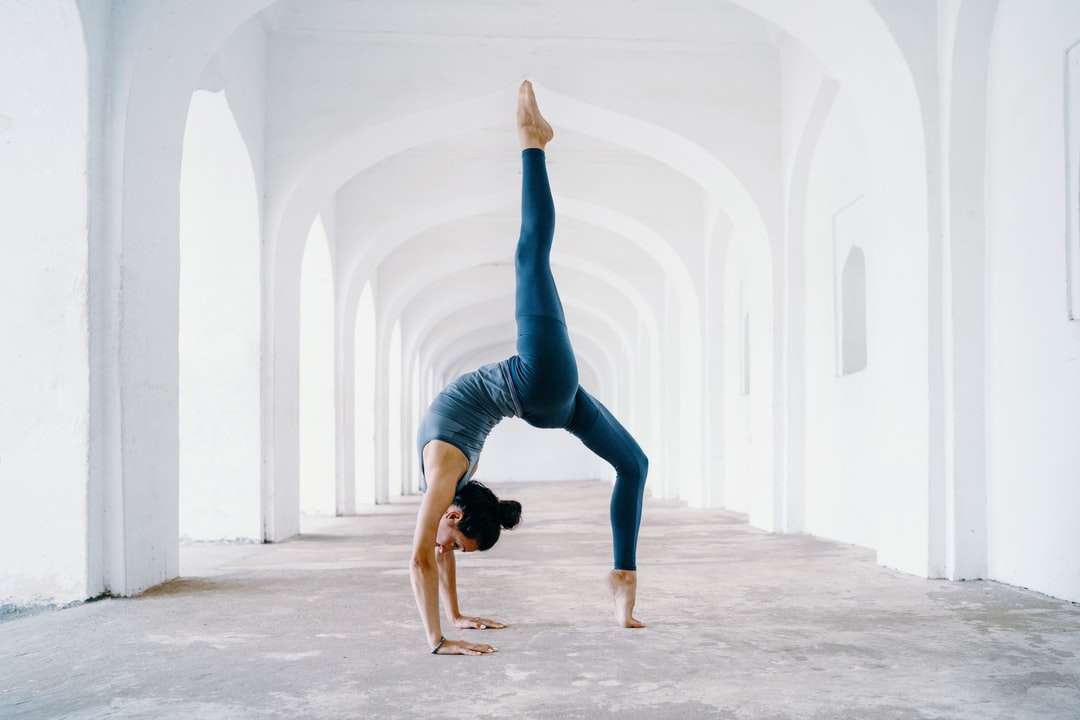 Femme en leggings bleus et débardeur noir faisant du yoga puzzle en ligne