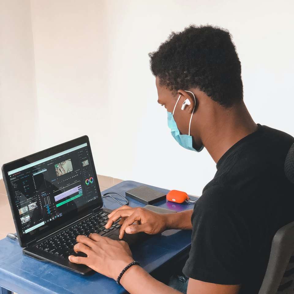 férfi fekete nyakú pólóban fekete laptop számítógépet használ kirakós online
