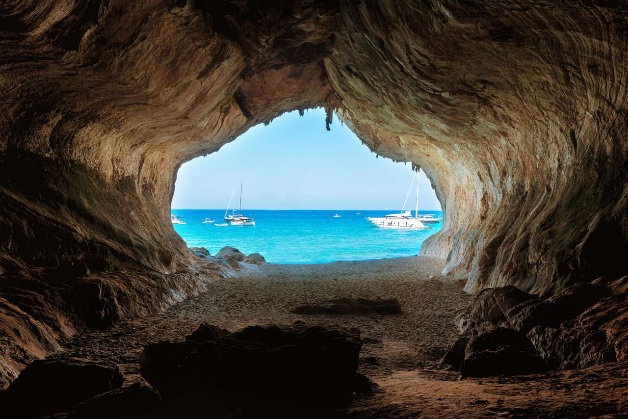 Blick von der Innenseite der großen Höhle zum Strand und dem blauen Meer. Mittelmeerküste, Sardinien, Italien. Online-Puzzle