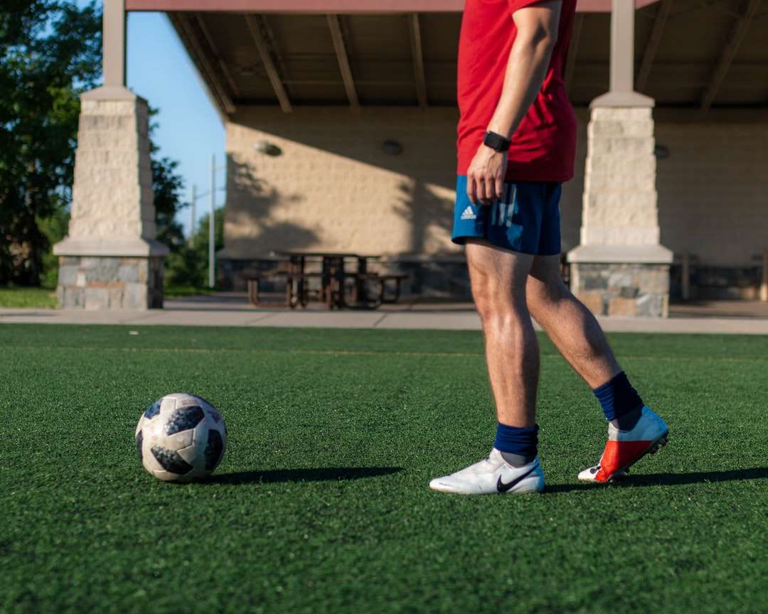 Homem, em, camisa vermelha, e, azul, shorts jogando futebol quebra-cabeças online
