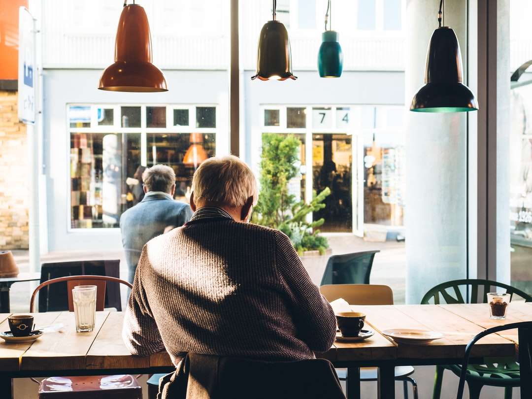 hombre en silla con mesa junto al café rompecabezas en línea