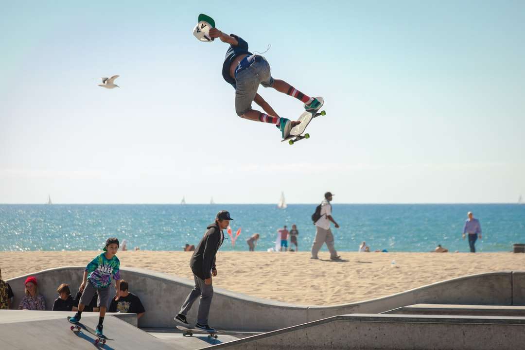 три человека играют на скейтборде на берегу моря пазл онлайн