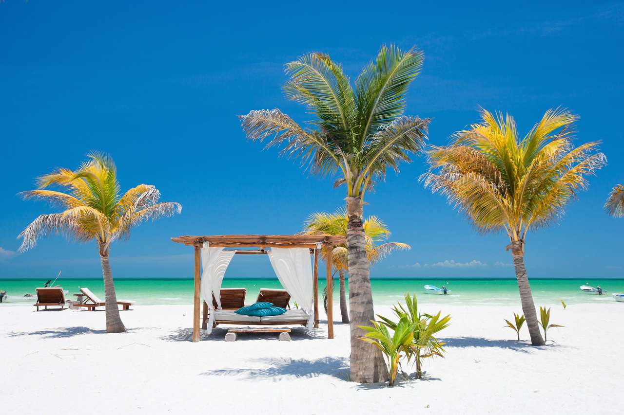 Camas de playa entre palmeras en la costa tropical perfecta. rompecabezas en línea