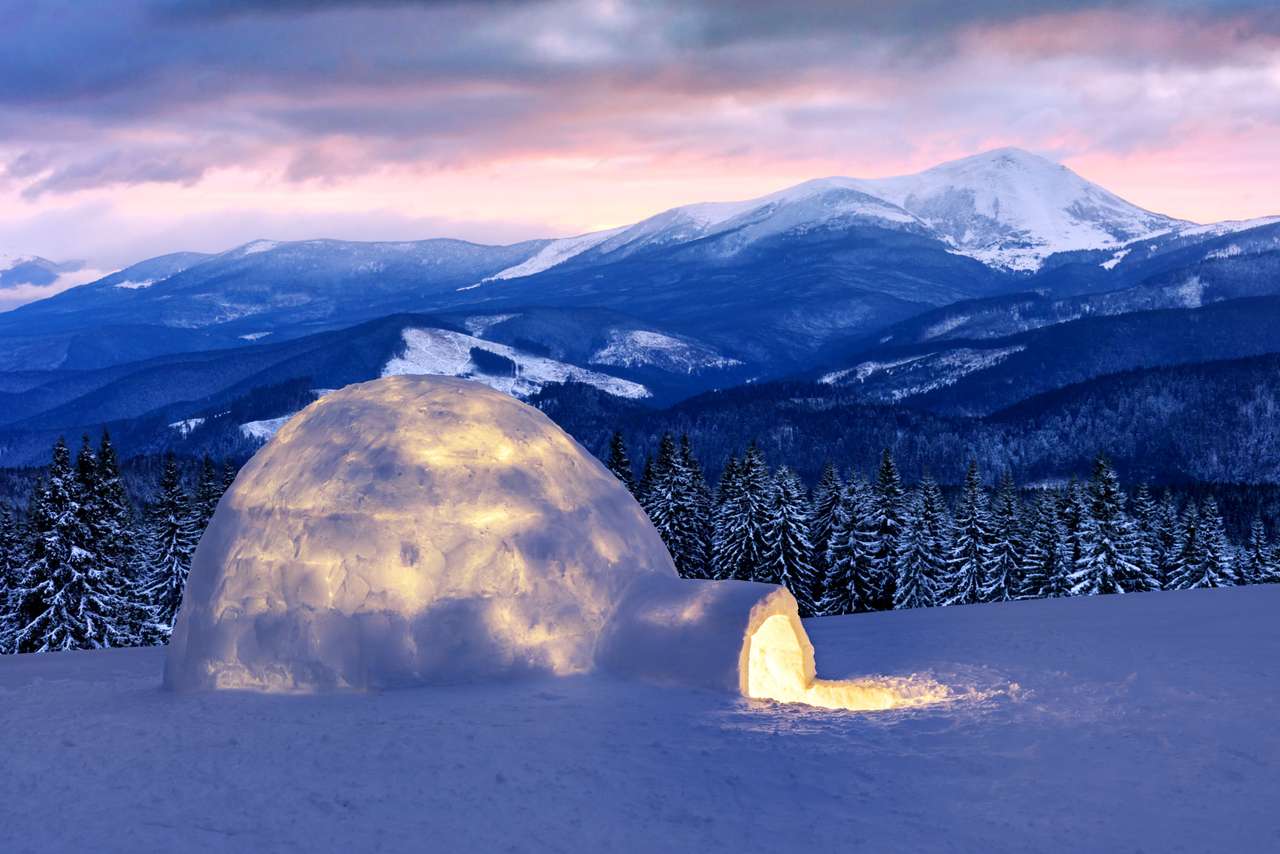 Casa de Igloo de nieve real en las montañas de invierno. Abetos cubiertos de nieve y picos de montaña en el fondo. Bosque brumoso con abeto nevado rompecabezas en línea