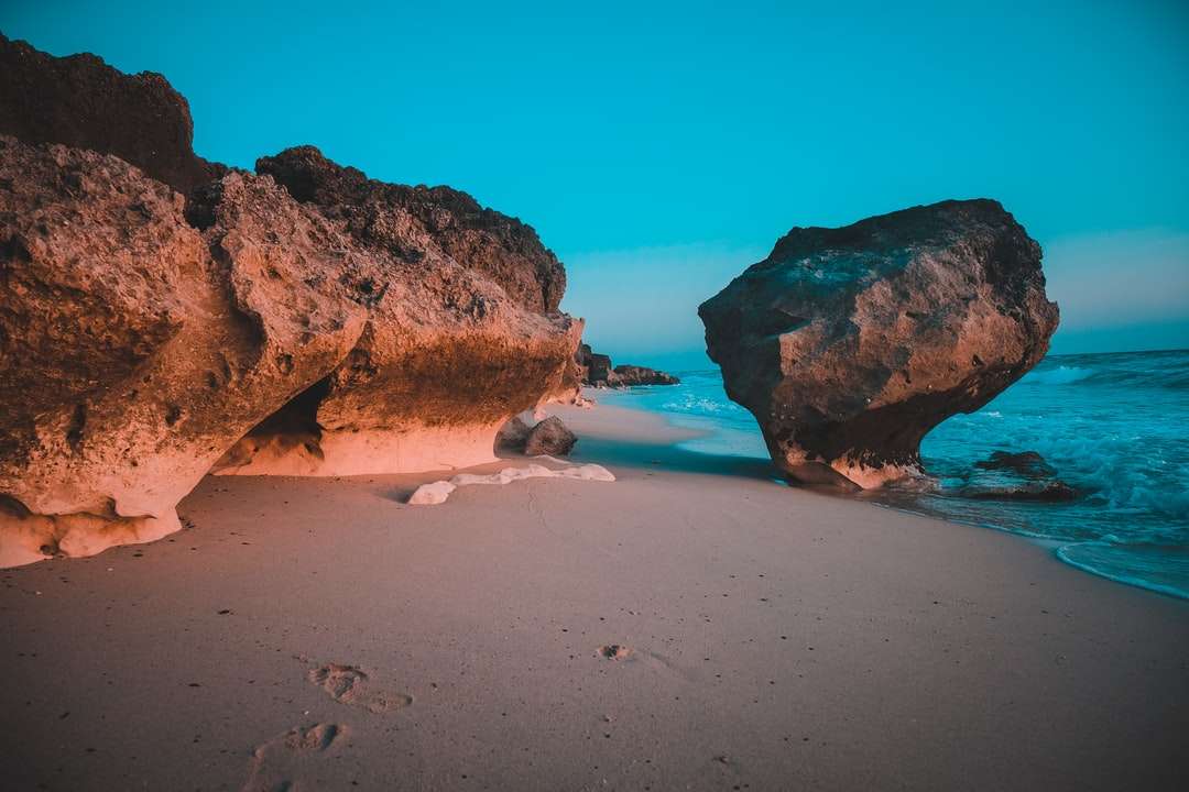 hnědá skalní útvar na pláži s pískem během dne online puzzle