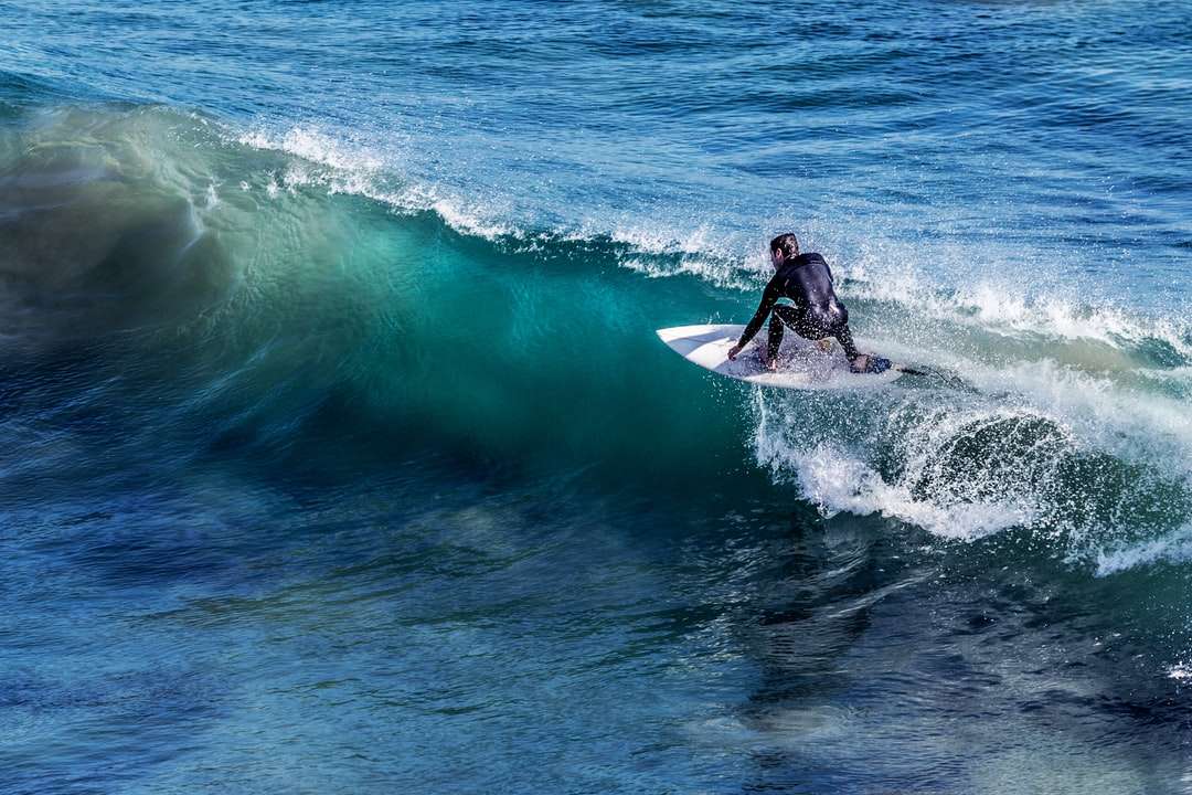 Persona en la tabla de surf blanca rodeada de agua azul del océano. rompecabezas en línea