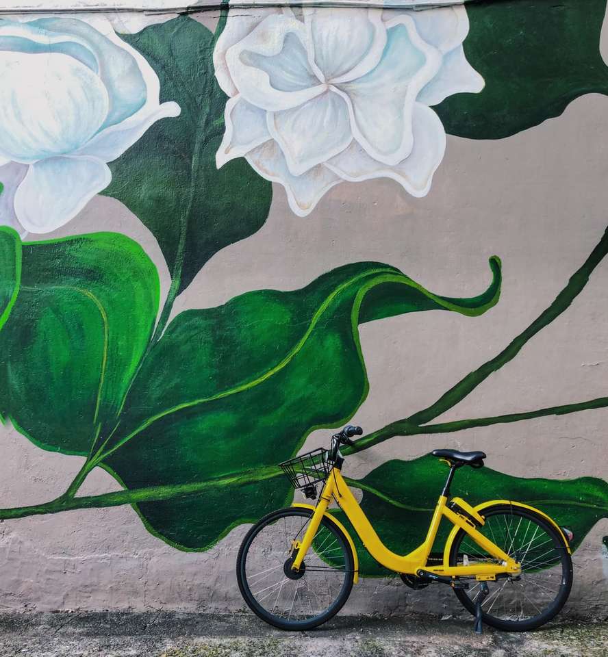 Gul cykel parkerad bredvid vita blommor graffiti pussel på nätet