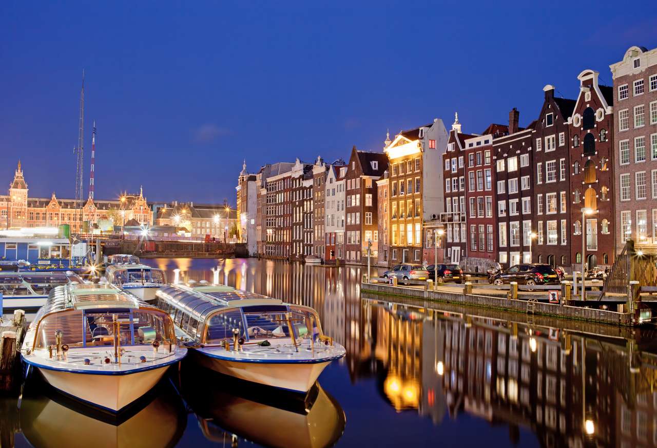 Ciudad de Amsterdam en Países Bajos en la noche, casas históricas de apartamentos con reflejos sobre el agua y los barcos listos para los recorridos por canales y cruceros. rompecabezas en línea