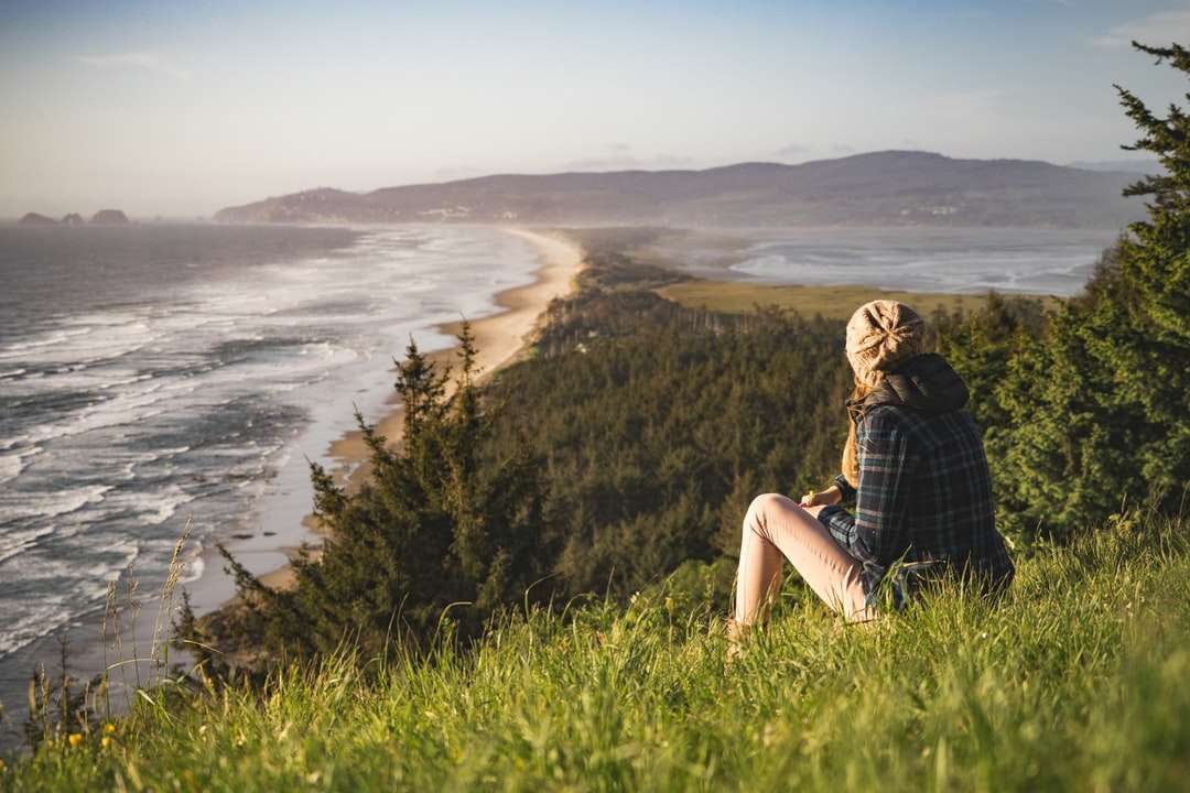 személy ül a dombon az óceán közelében napközben kirakós online