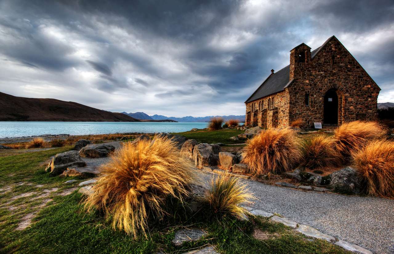 chiesa tranquilla vicino a un lago glaciale sullo sfondo di una montagna puzzle online