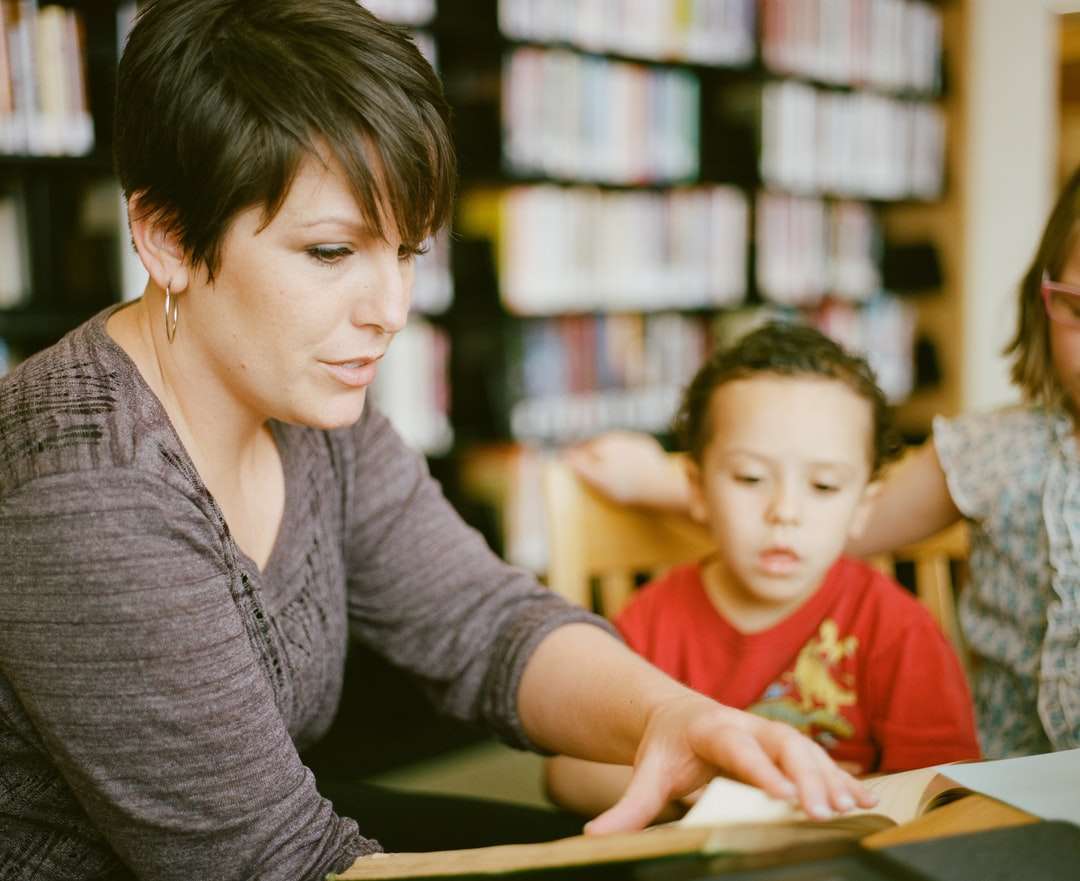 femme en chemise grise à manches longues assise à côté d'un garçon puzzle en ligne
