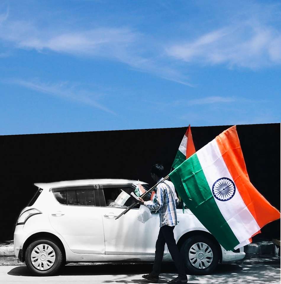 чоловік тримає прапор Індії біля білого автомобіля онлайн пазл