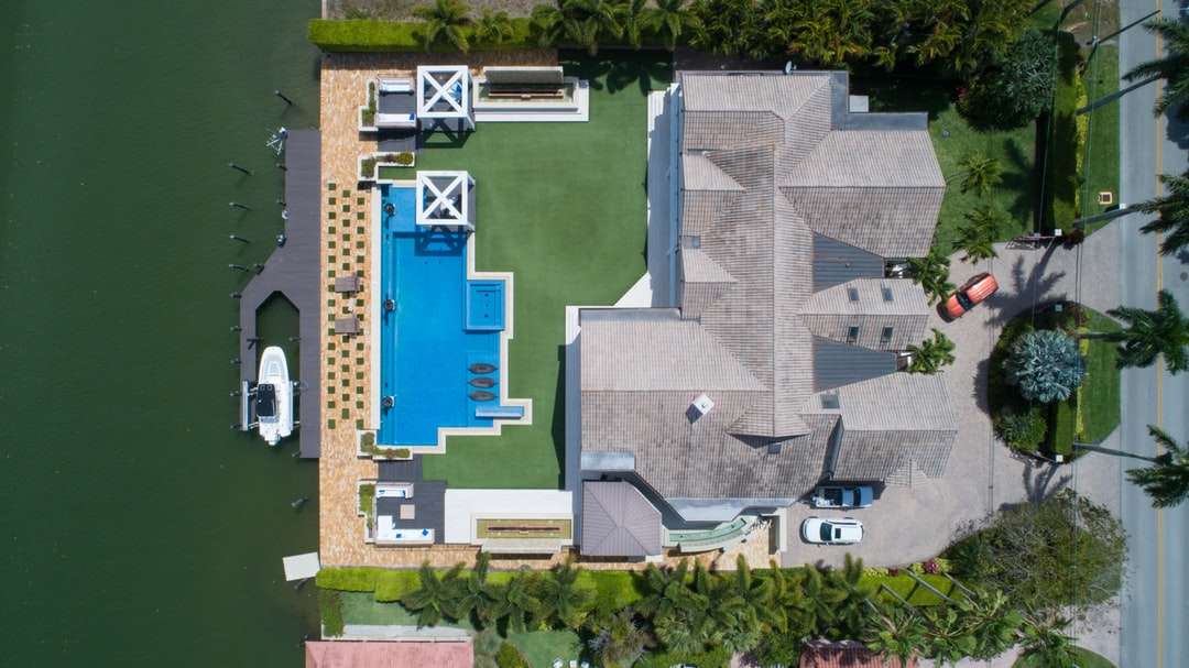 pohled z ptačí perspektivy na dům s bazénem u vodní plochy skládačky online