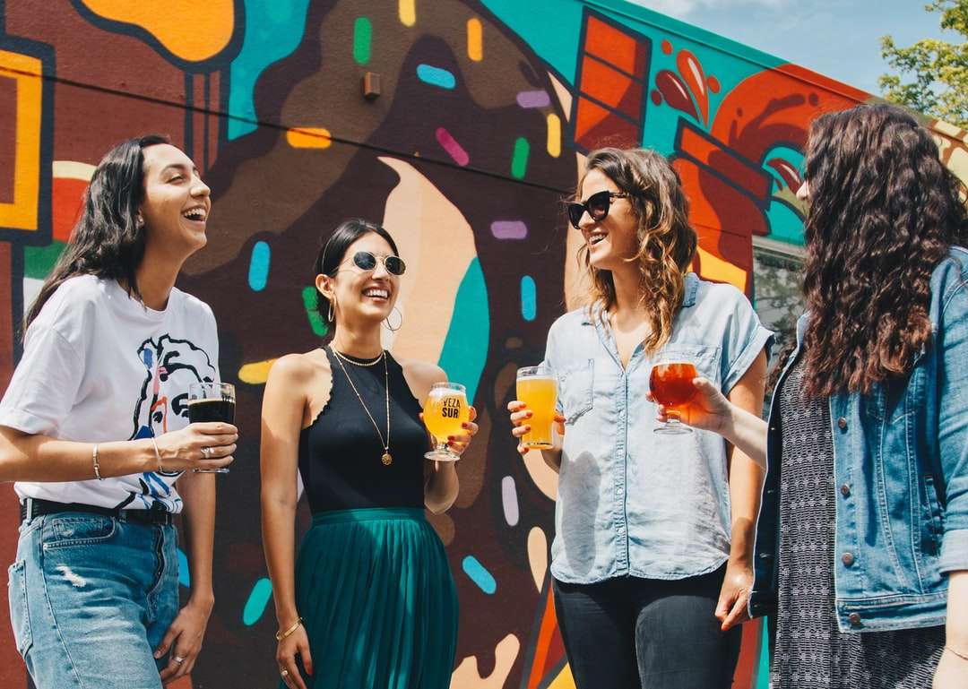 vier vrouwen met drankjes terwijl ze samen lachen legpuzzel online