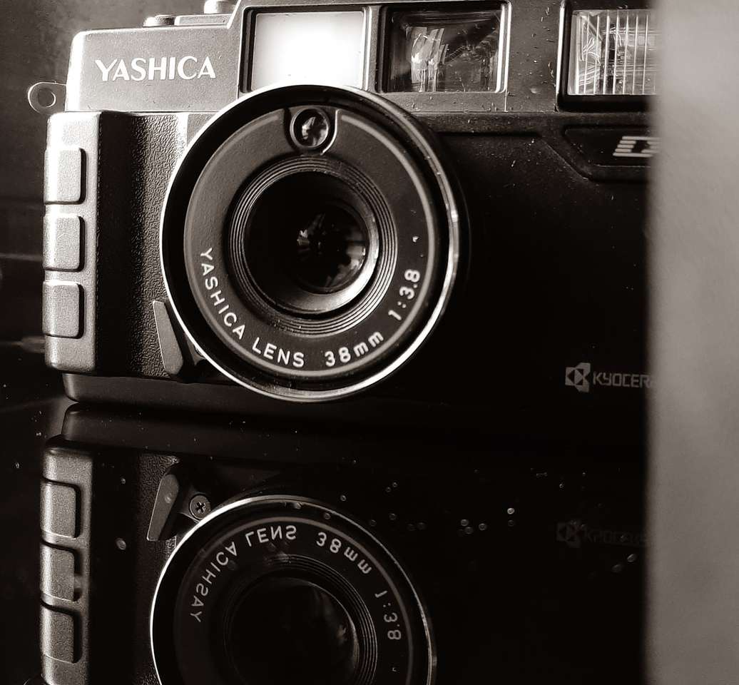 μαύρη και ασημί κάμερα σε λευκή επιφάνεια παζλ online