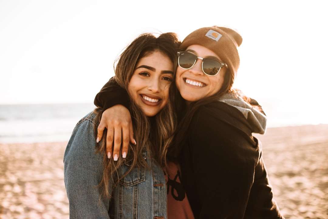 donna che abbraccia un'altra donna mentre sorride in spiaggia puzzle online