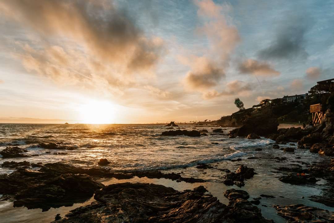 havsvågor som kraschar på stenar under solnedgången pussel på nätet