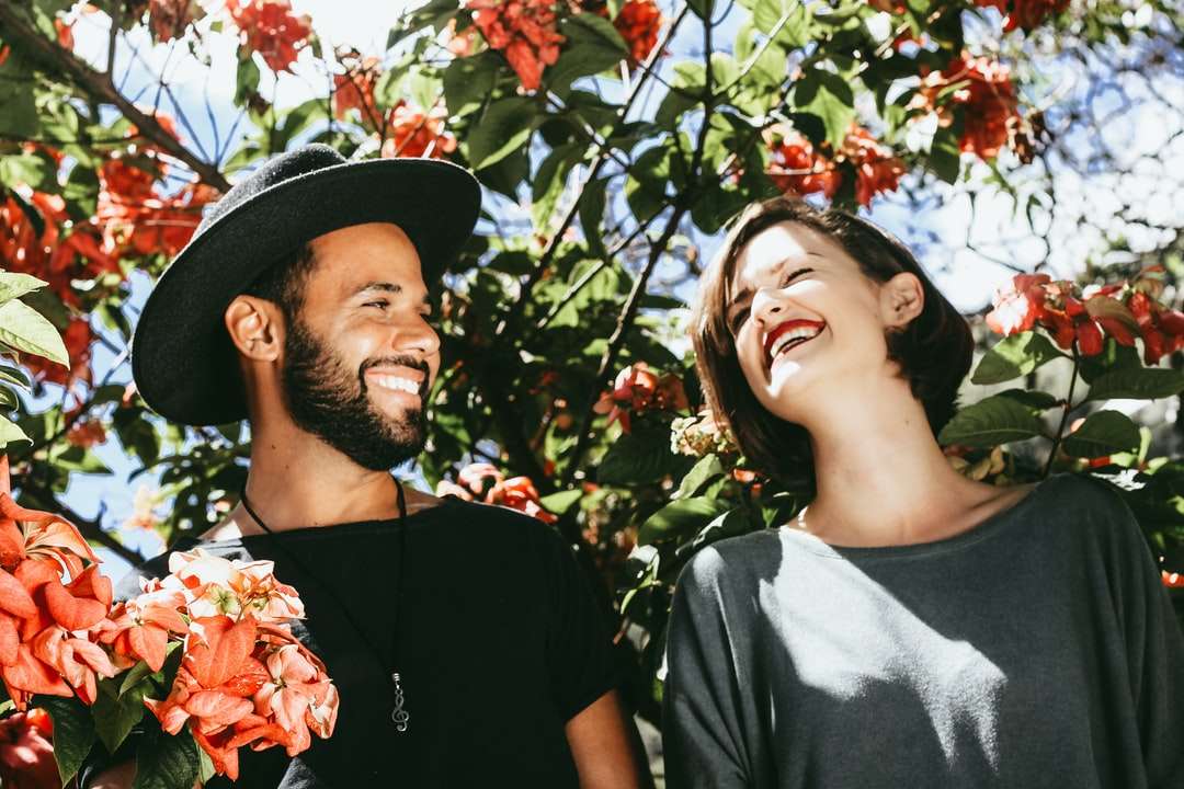 man en vrouw omringd door rode en groene bloemenbomen legpuzzel online