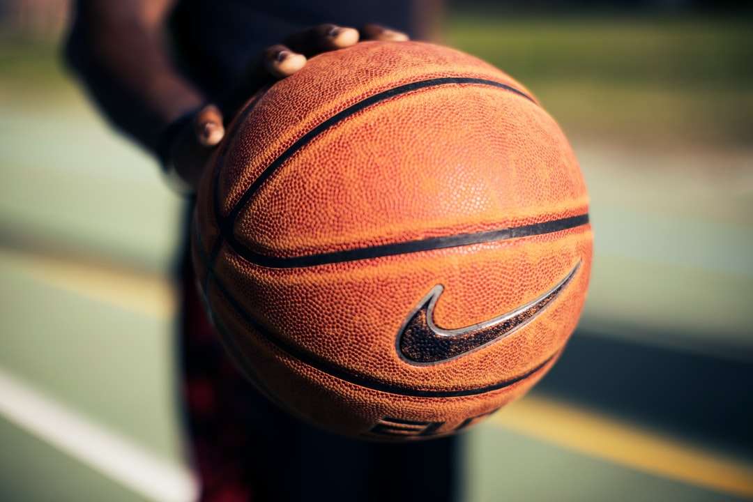 Persona sosteniendo baloncesto Nike marrón rompecabezas en línea