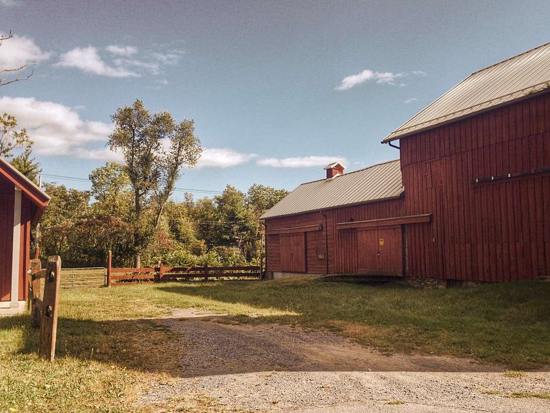 hnědá dřevěná stodola poblíž zelených stromů pod modrou oblohou skládačky online