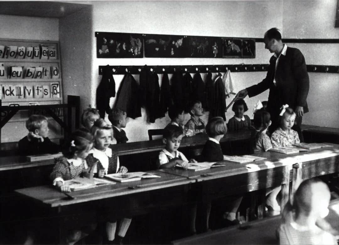 fotografia in scala di grigi di bambini seduti all'interno della stanza puzzle online