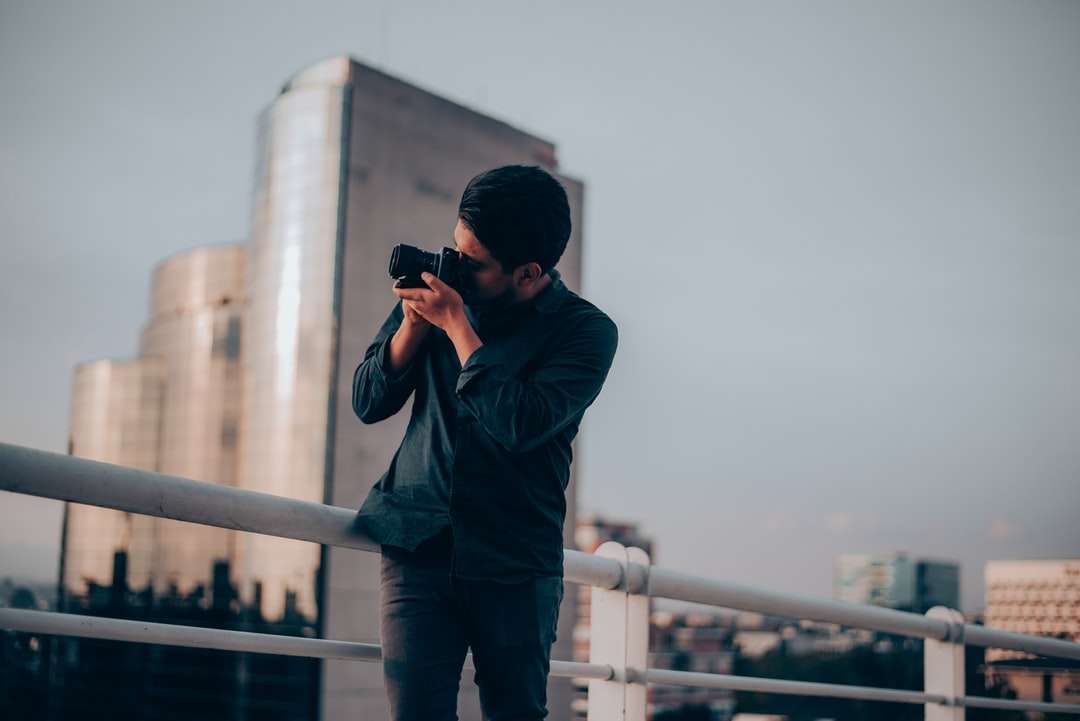 hombre con camisa negra usando una cámara réflex digital rompecabezas en línea