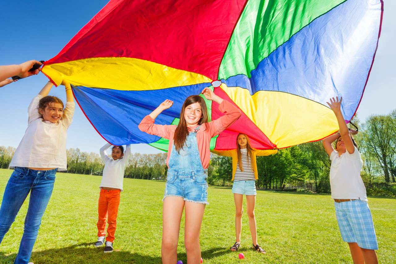 Kinder spielen mit Regenbogenfallschirm im Park Puzzlespiel online
