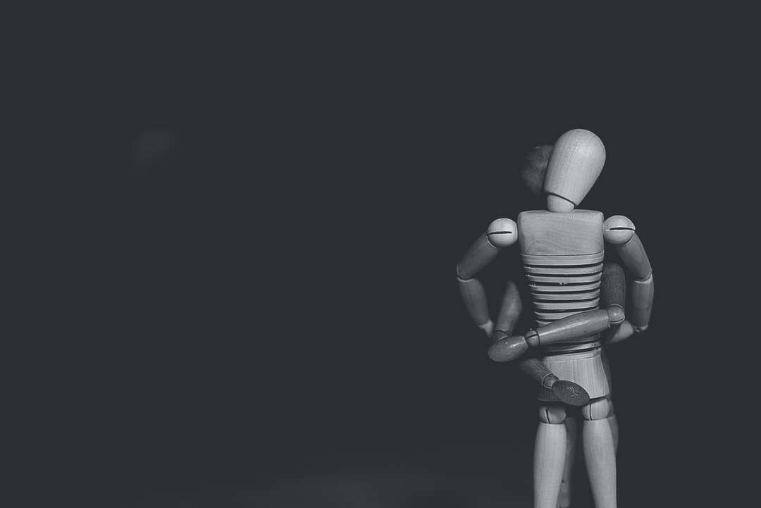 foto en escala de grises de una figura de acción conjunta abrazándose rompecabezas en línea