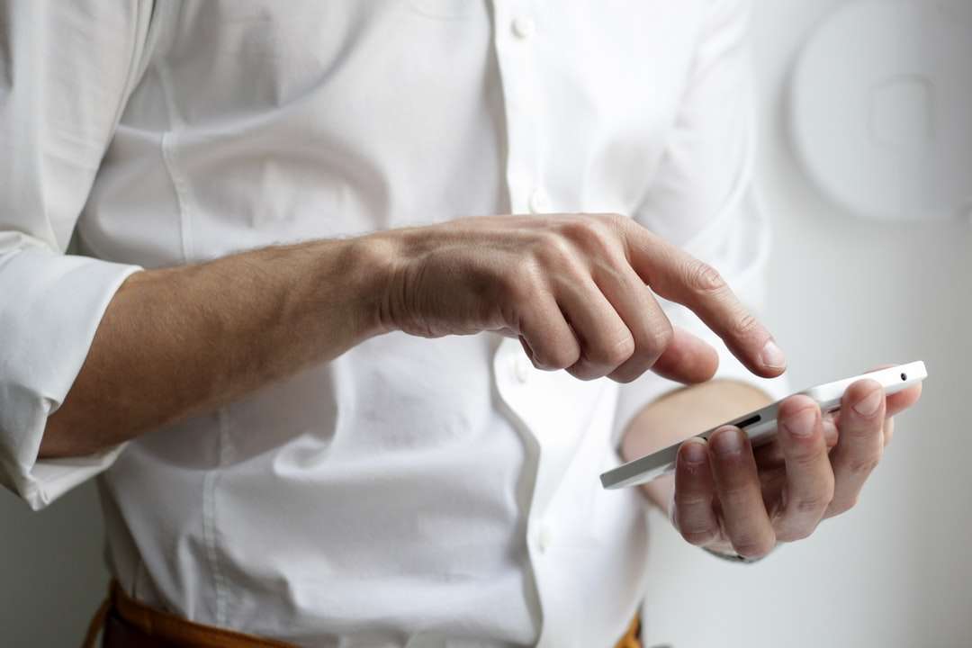 човек, който държи бял смартфон с Android в бяла риза онлайн пъзел
