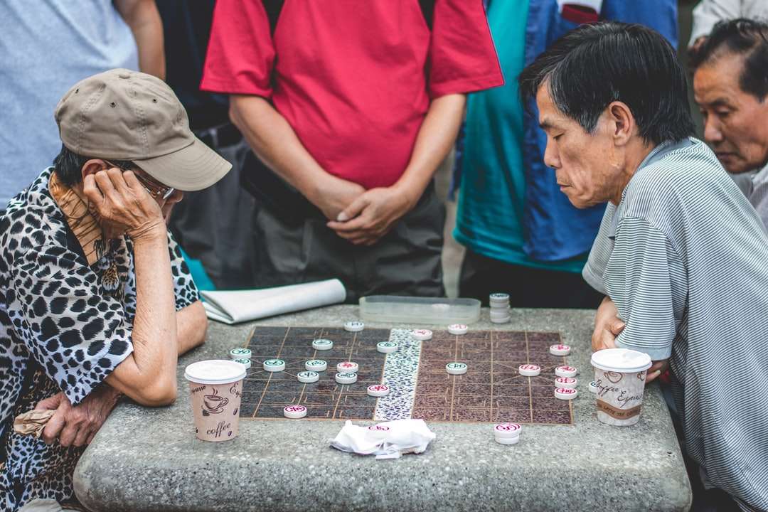 doi bărbați care stau lângă o masă și joacă un joc jigsaw puzzle online