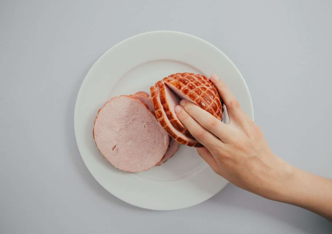person holding sliced ham in white ceramic plate jigsaw puzzle online