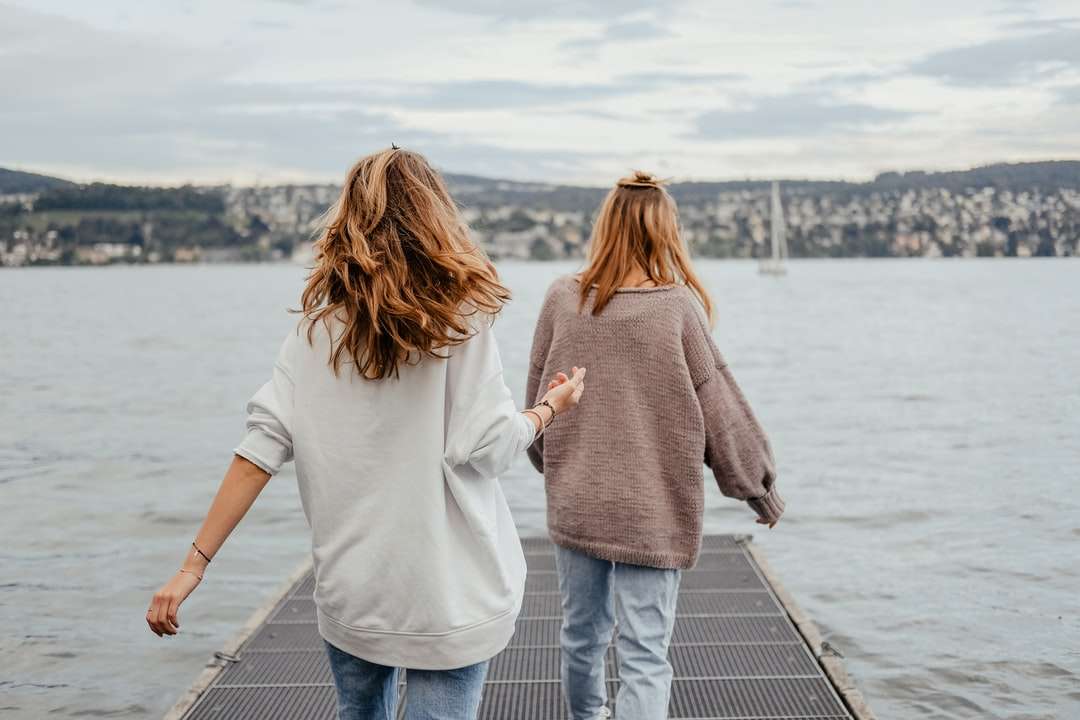 două femei care stau pe docul în fața mării în timpul zilei jigsaw puzzle online
