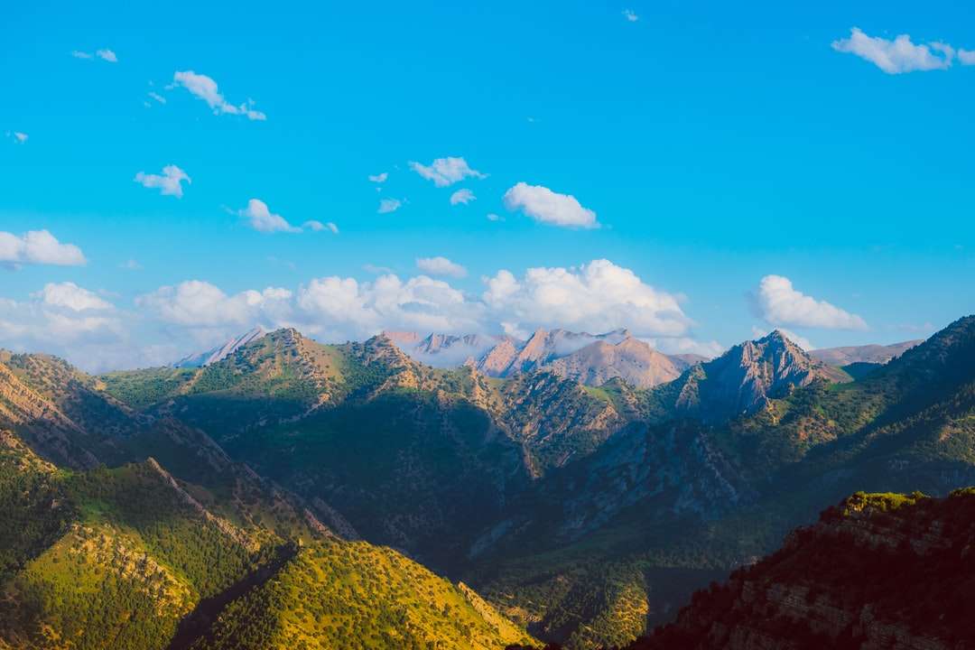 zelené a hnědé hory pod modrou oblohou během dne skládačky online
