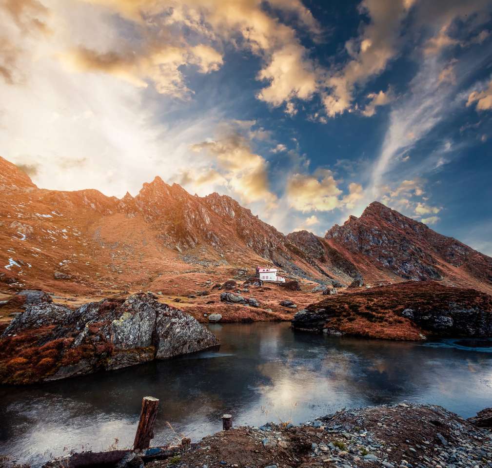 Lindo lago no sopé da montanha rochosa ao pôr do sol puzzle online