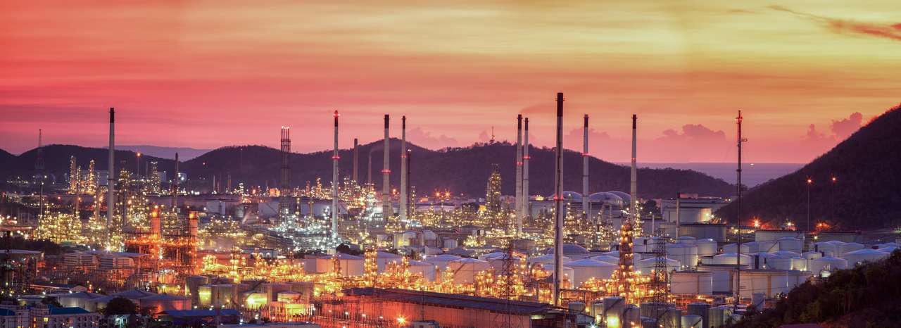 Raffineria di petrolio con tubo e serbatoio dell'olio lungo il cielo al crepuscolo puzzle online