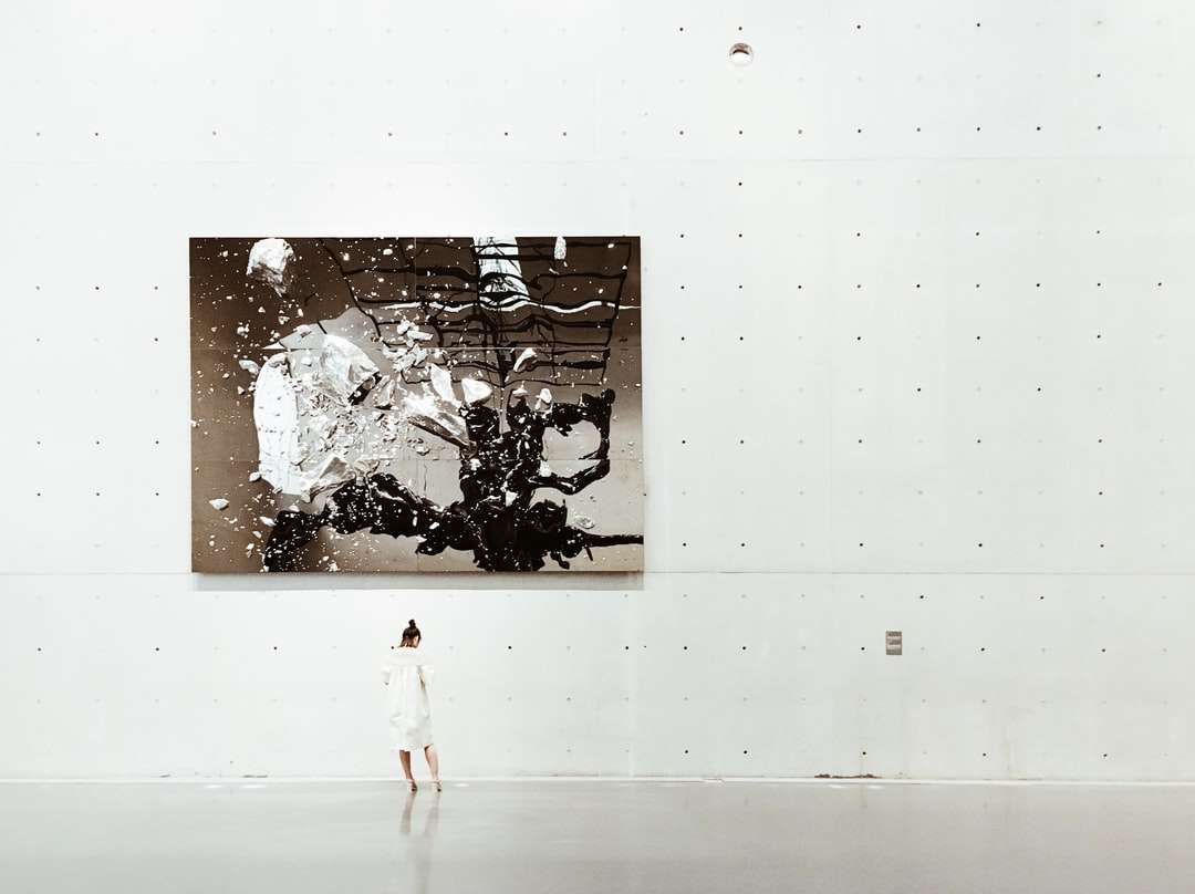 Uma mulher em pé perto de uma pintura em uma galeria de arte moderna puzzle online