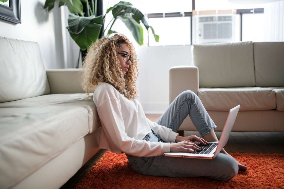 жена, седнала на пода и облегната на дивана с лаптоп онлайн пъзел
