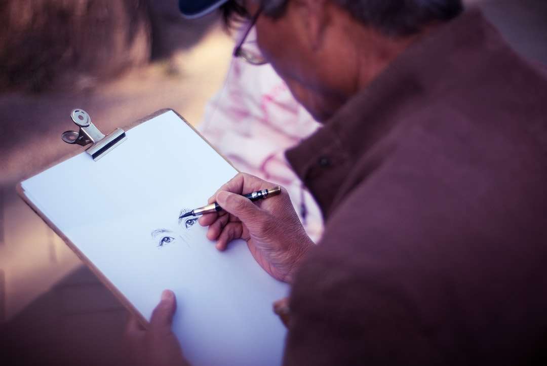 мъж, скициращ лице върху бяла хартия за принтер онлайн пъзел
