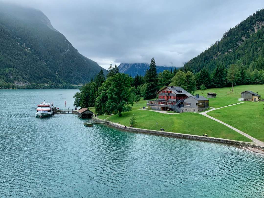 casă albă și roșie lângă lac și copaci verzi în timpul zilei jigsaw puzzle online