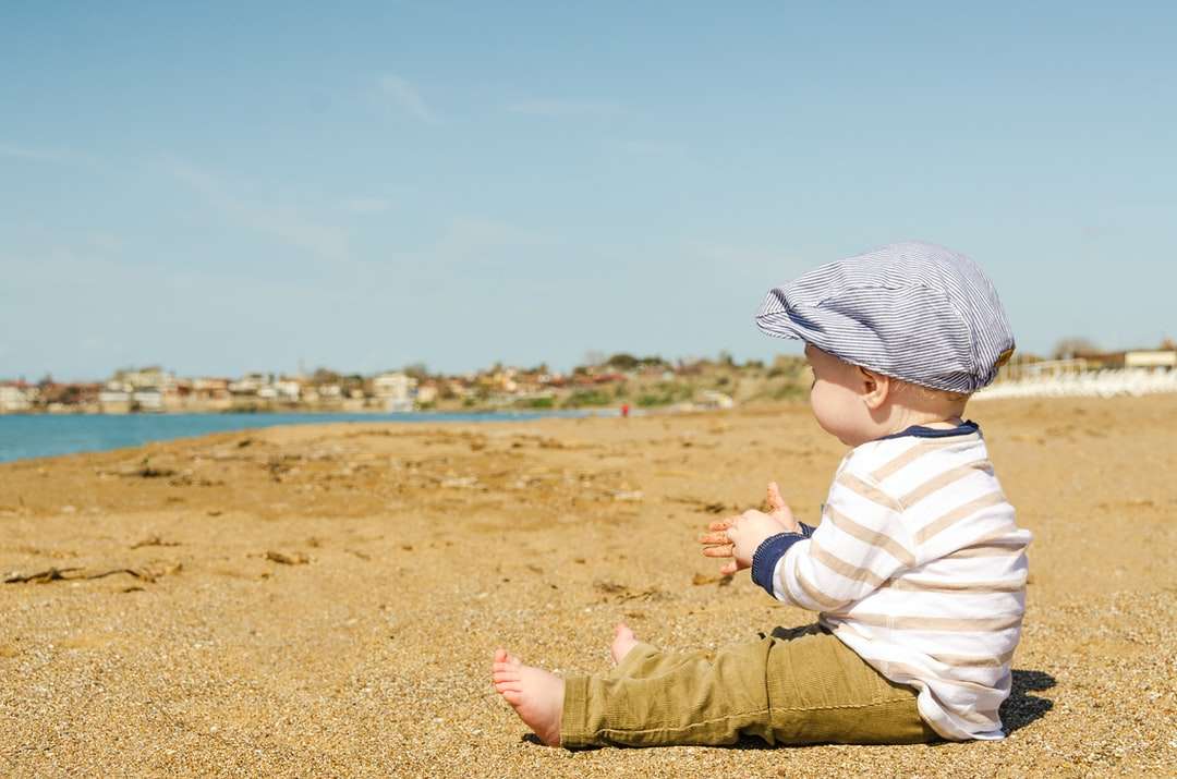 sittande litet barn på stranden på dagtid Pussel online