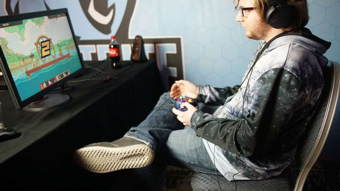 мужчина сидит и играет в видеоигру с помощью панели управления онлайн-пазл