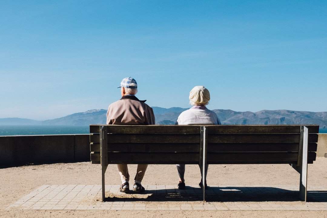 homem e mulher sentados no banco de frente para o mar puzzle online