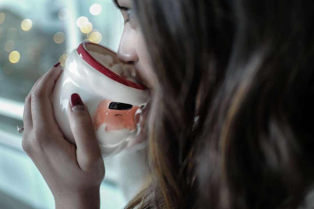 kvinna som dricker på vit och röd keramisk mugg Pussel online