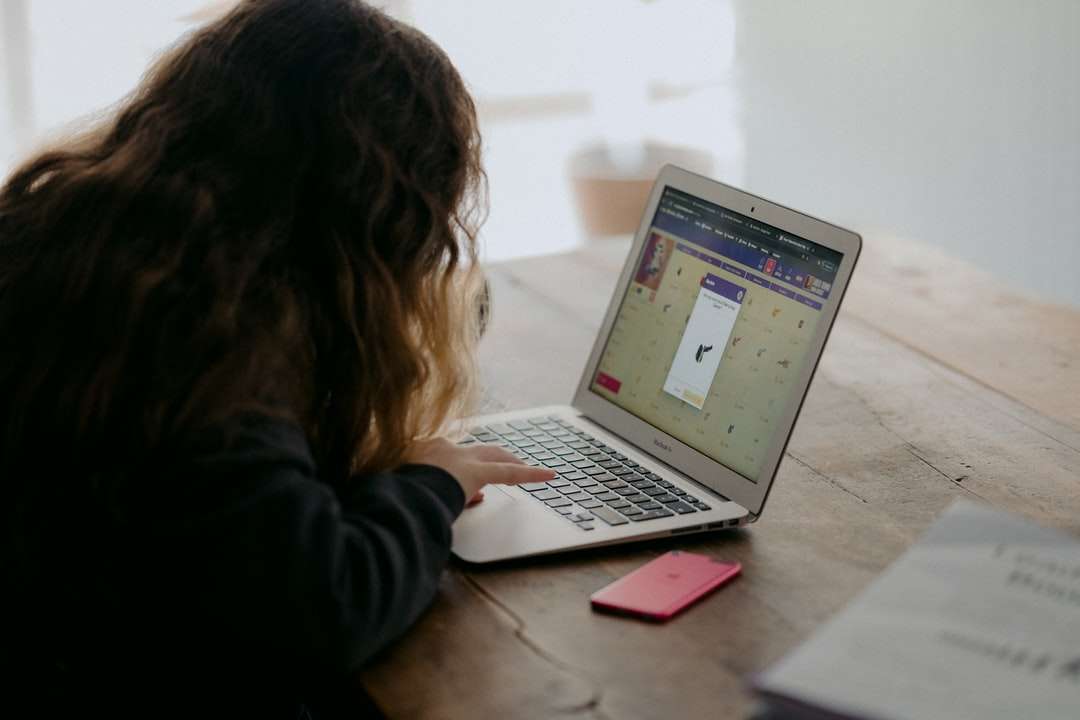 mujer con camisa negra de manga larga usando macbook air rompecabezas en línea