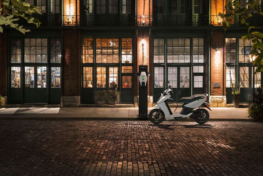 черно-белый мотороллер припаркован рядом с коричневым зданием онлайн-пазл